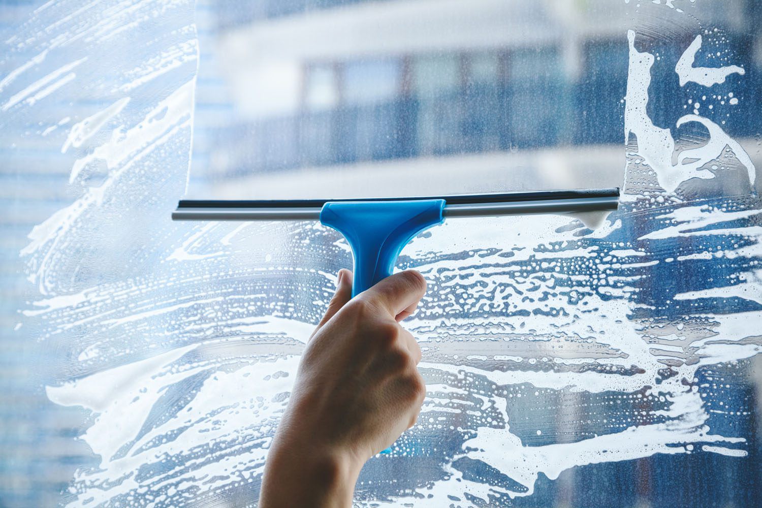 Ein Fenster wird mit einem Abzieher und Reinigungsmittel gereinigt.